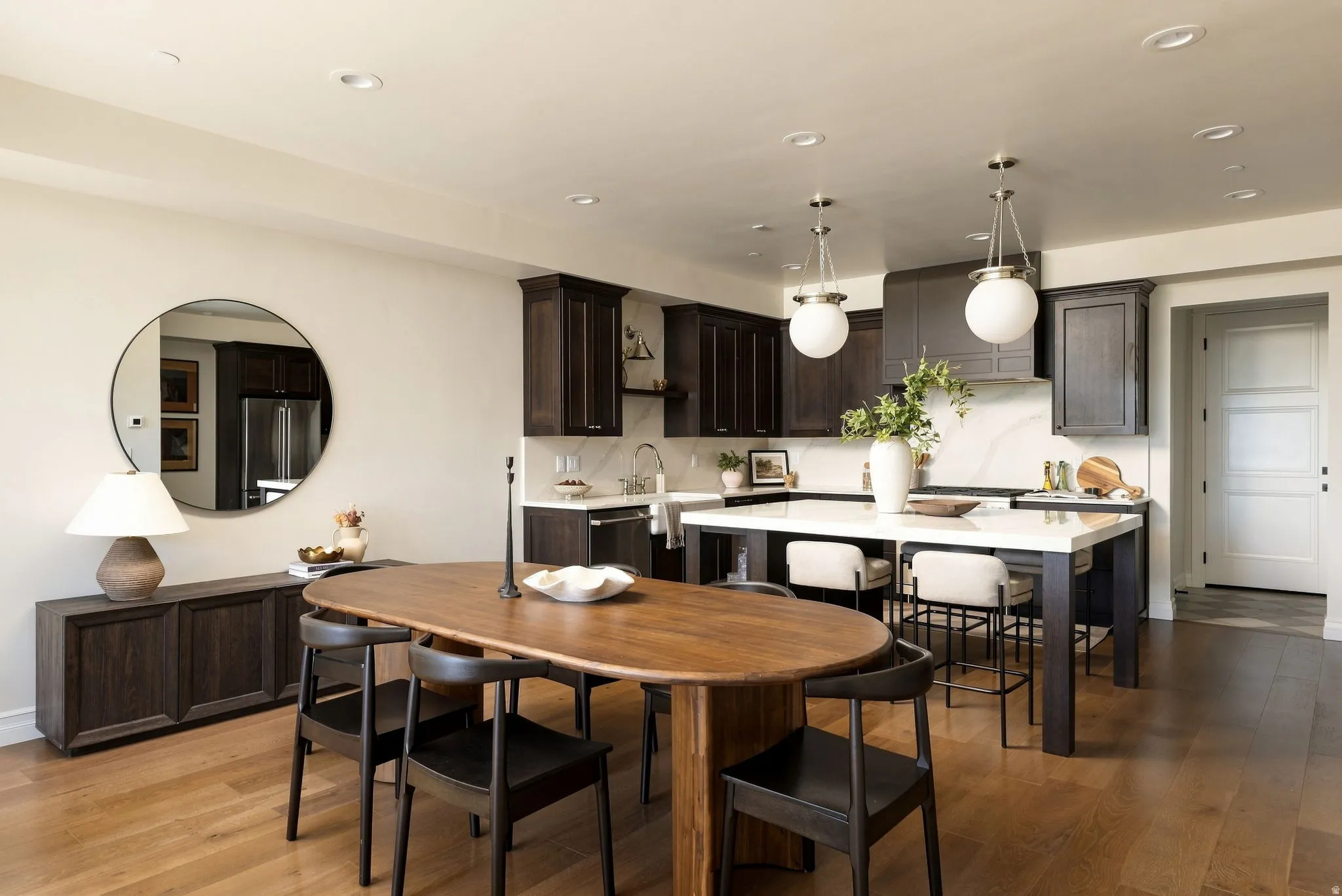 Kitchen featuring dark wood cabinetry, white stone countertops, integrated range hood, recessed lighting, and wood-finish flooring