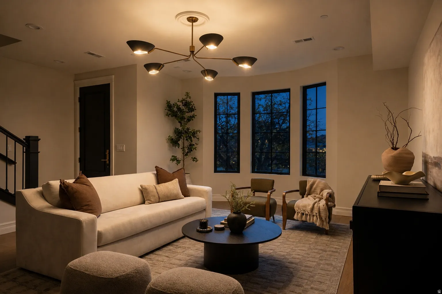 Living area with a contemporary chandelier, recessed lighting, and a bay window featuring three dark-framed windows