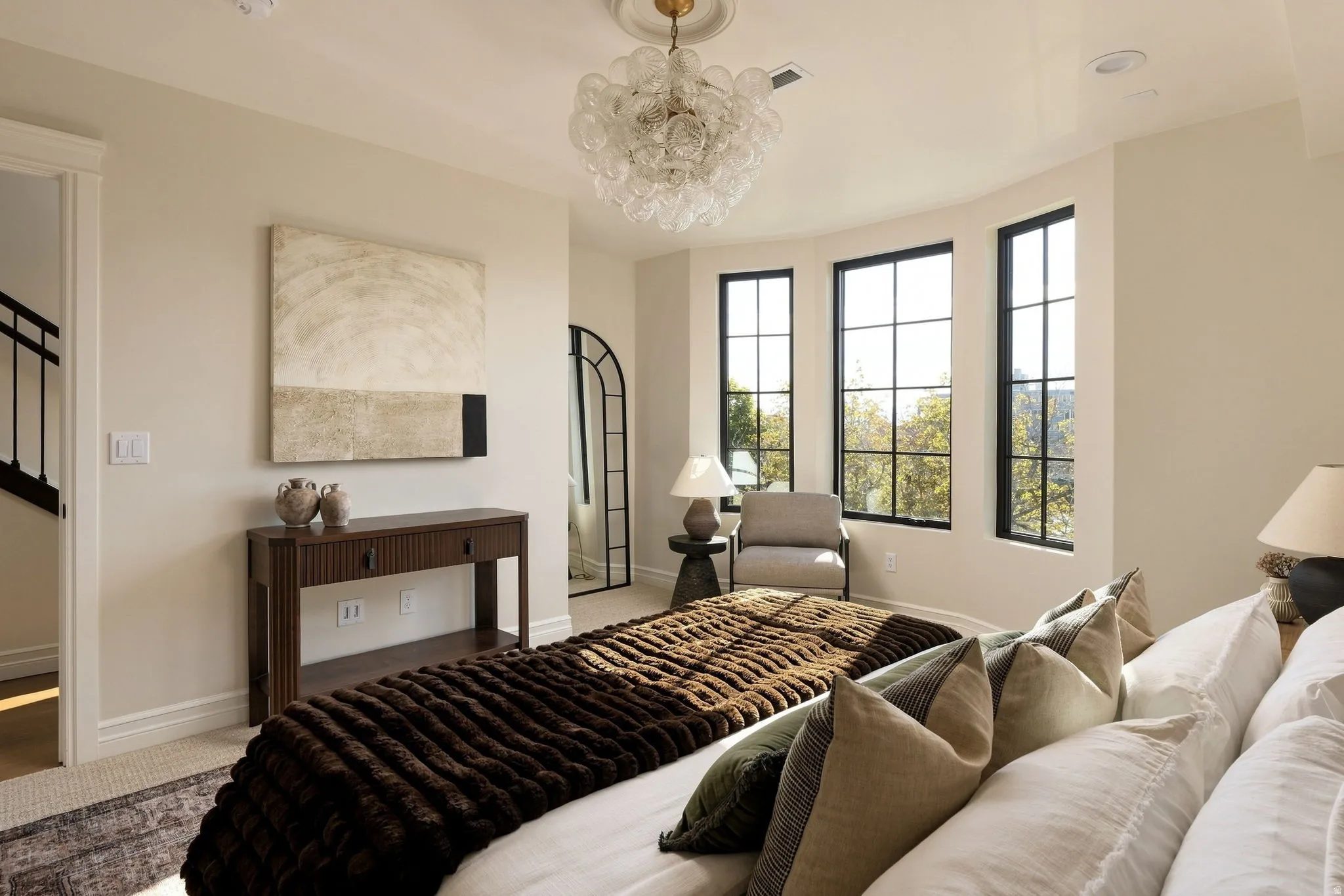 Bay window with three floor-to-ceiling windows, sculptural glass chandelier, recessed lighting, and wood-finish console table