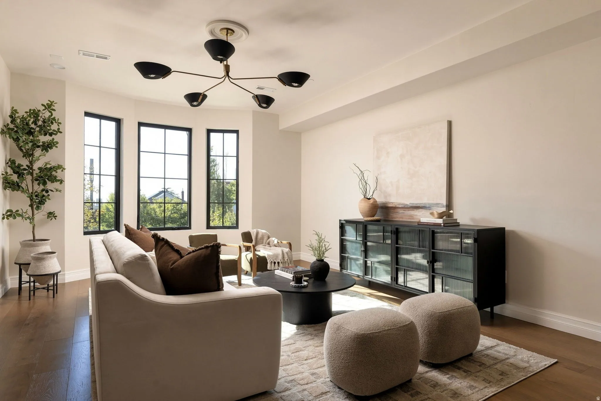 Bay window featuring three large paneled windows, wood-finish flooring, and a modern ceiling light fixture