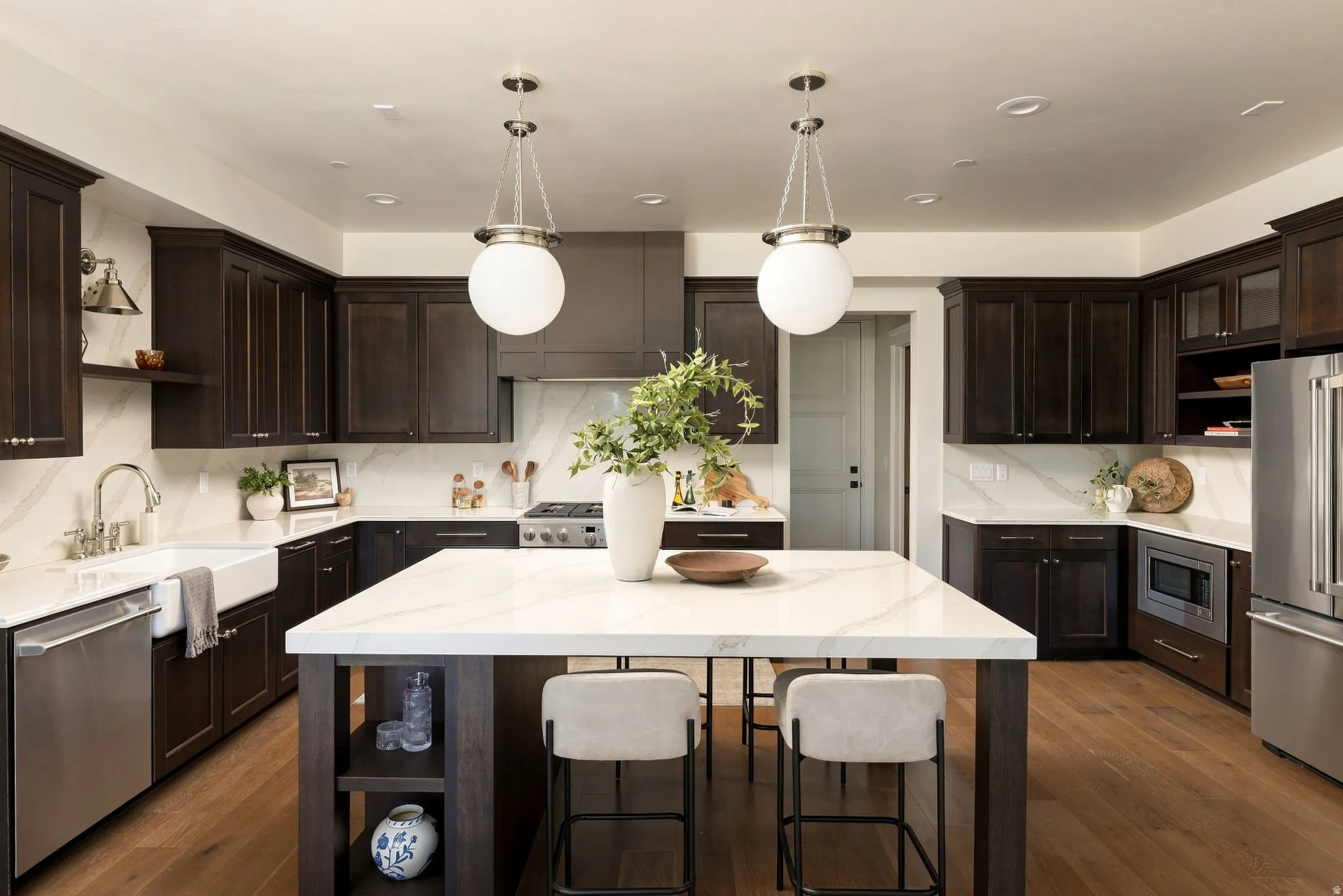 Kitchen featuring dark wood cabinetry, a large center island with a stone countertop, stainless steel appliances, and wood-finish flooring