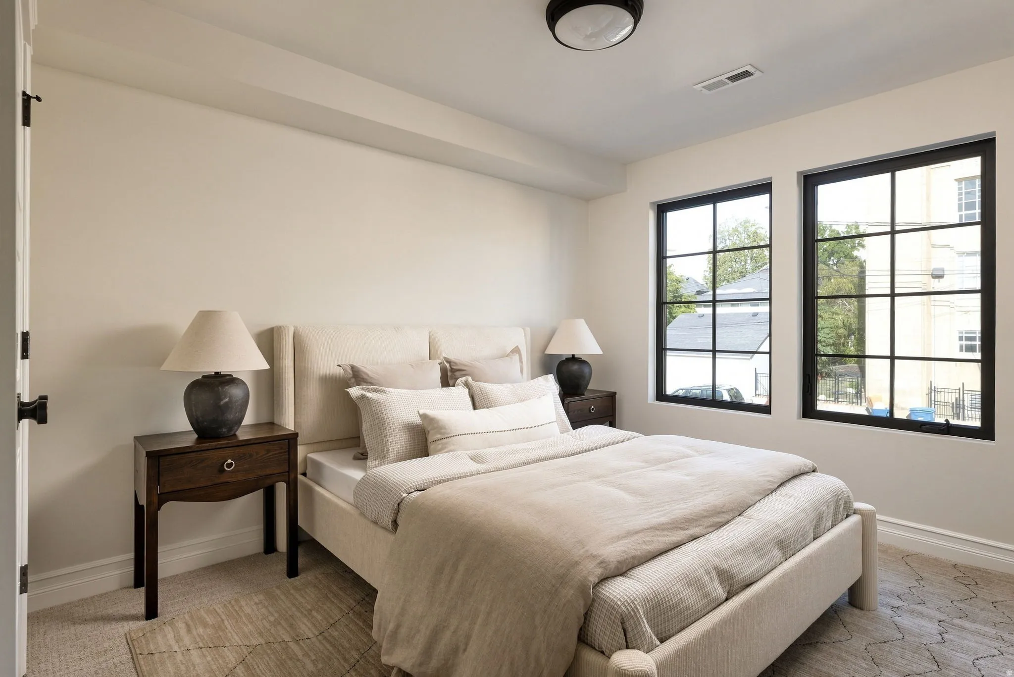 Wall-to-wall carpeting with a geometric pattern, contemporary black-framed windows, and a flush mount ceiling light fixture