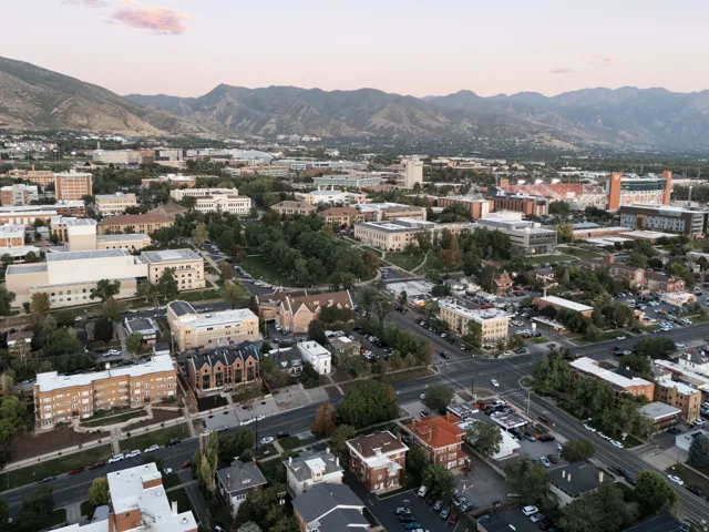 Aerial perspective showcasing a diverse urban landscape with prominent institutional buildings, extensive green spaces, and a mountainous backdrop