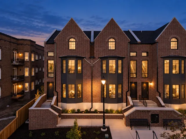 Brick townhome exterior featuring an arched window, multiple bay windows, and a prominent gable roofline
