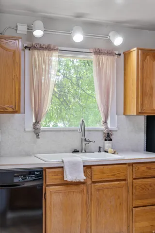 Kitchen window with track lighting, an integrated sink, a gooseneck faucet, and wood cabinetry