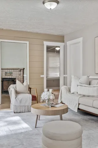 Shiplap accent wall, recessed ceiling lighting, light wood-finish flooring, white trim work, and a fireplace with decorative tile surround
