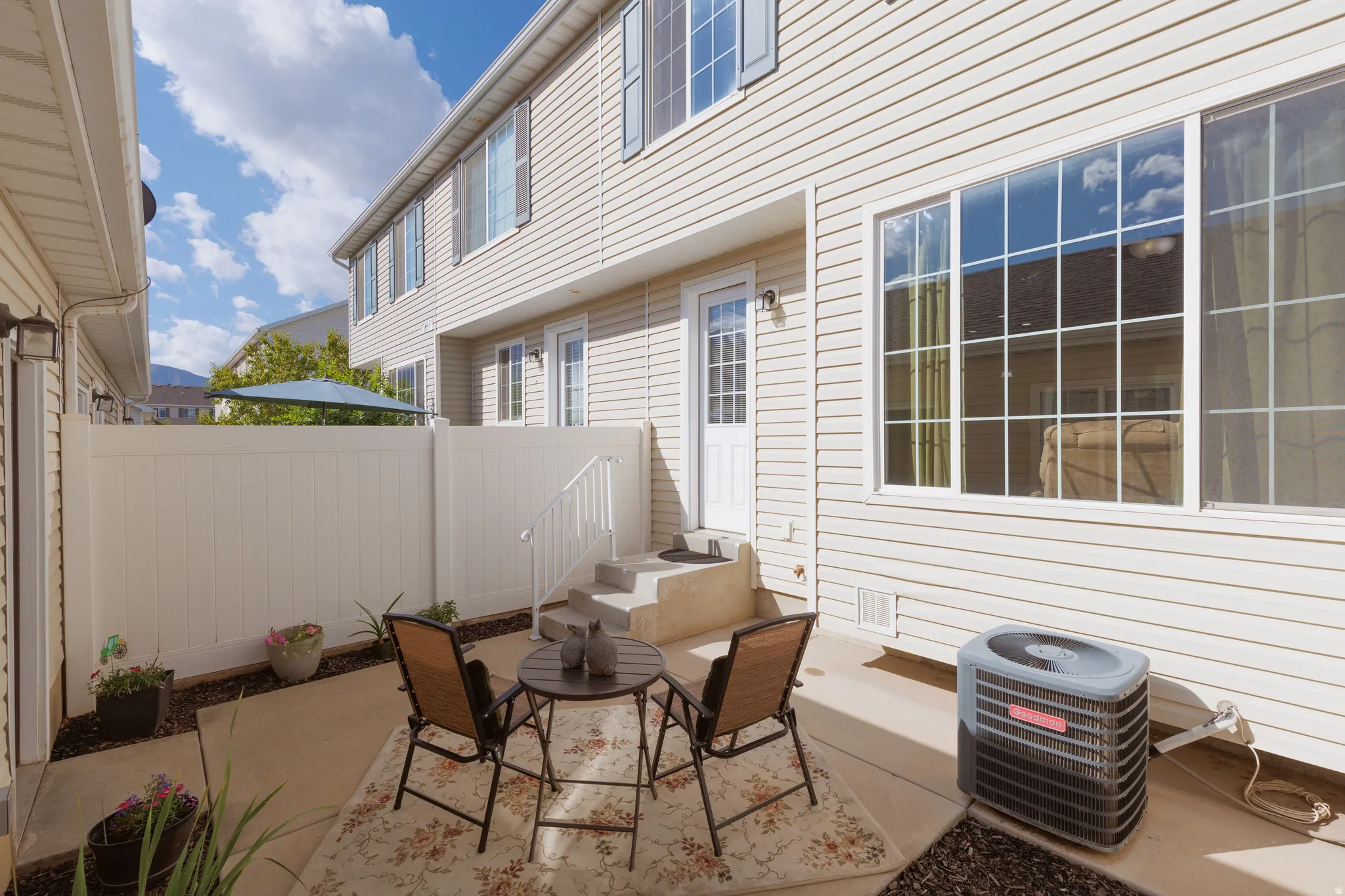 Private patio space with concrete flooring, white vinyl fencing, and direct access to the interior via a glass-paneled door