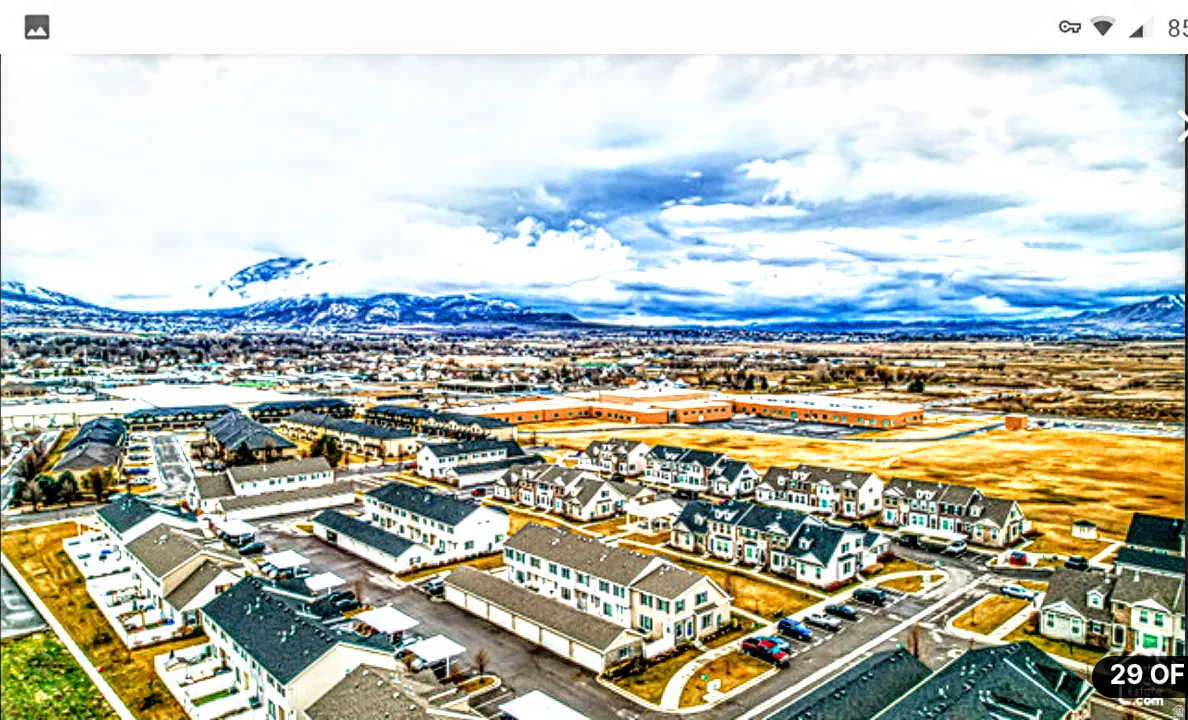 Expansive residential development featuring multiple housing styles, paved roadways, and a prominent mountain range backdrop