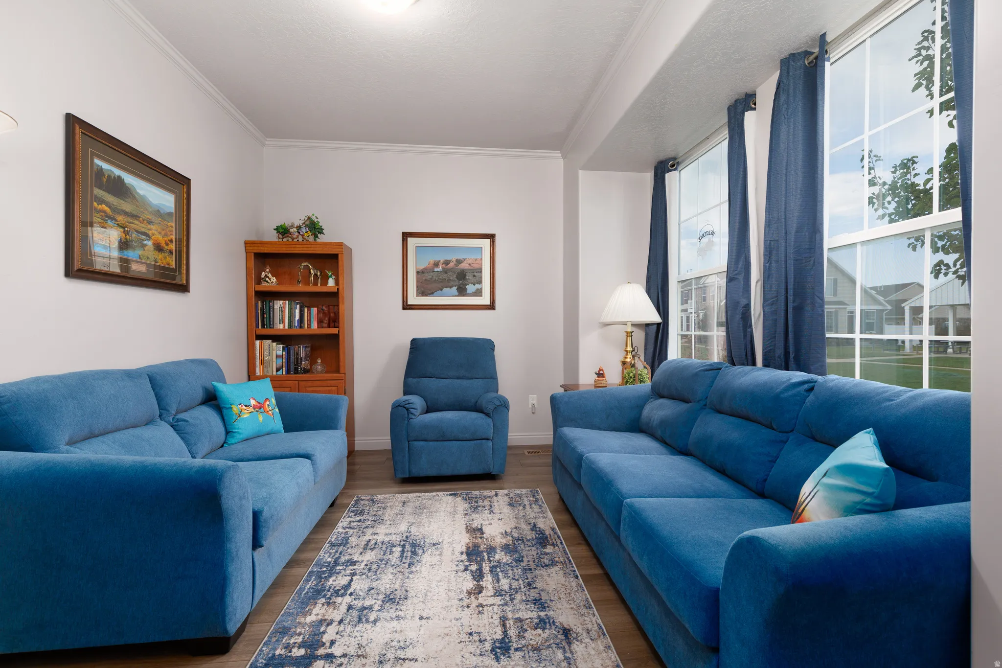 Bright living area featuring wood-finish flooring, white walls, and prominent window with natural light