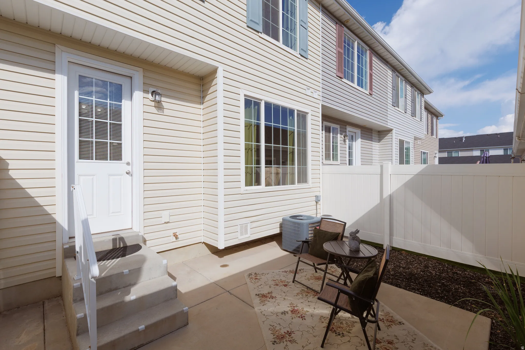Private patio with concrete flooring, full-light paneled exterior door, and vinyl fencing