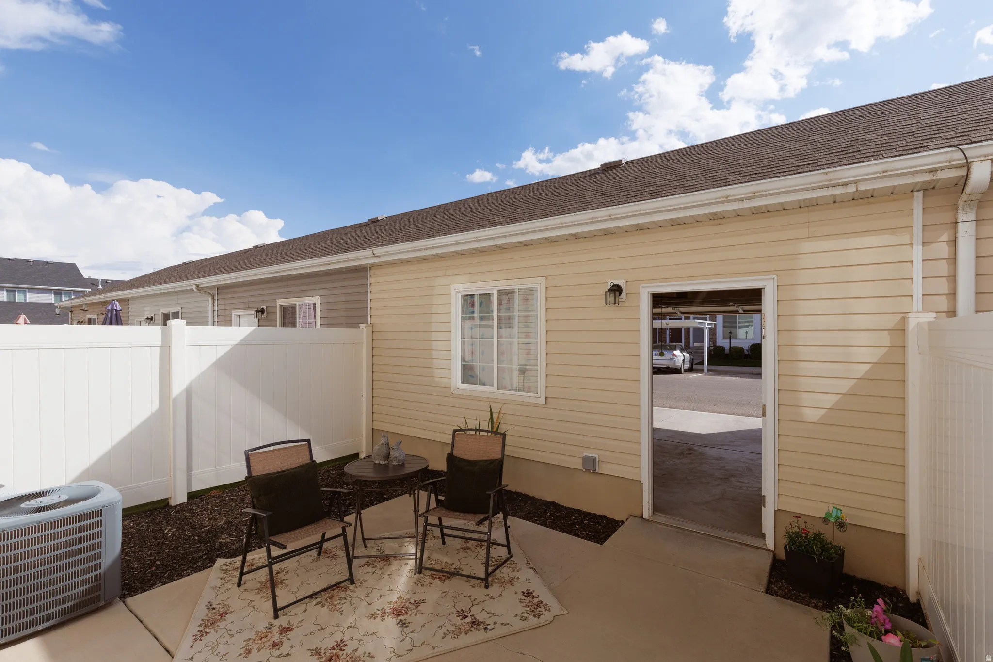 Private patio area with concrete slab, white vinyl fencing, and direct exterior access