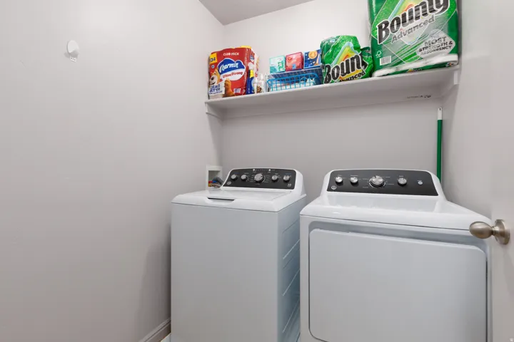 Laundry area featuring white appliances and an overhead storage shelf