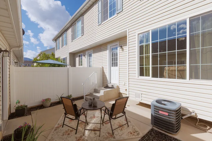 Private patio space with concrete flooring, white vinyl fencing, and direct access to the interior via a glass-paneled door
