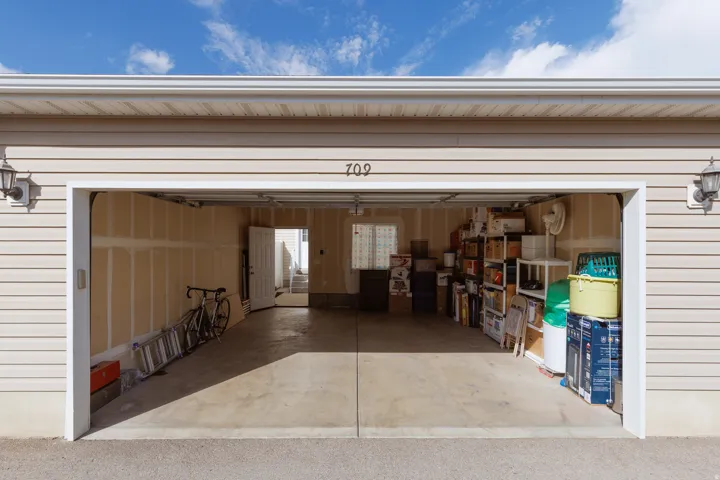 Two-car garage with concrete flooring, overhead garage door, and interior access door