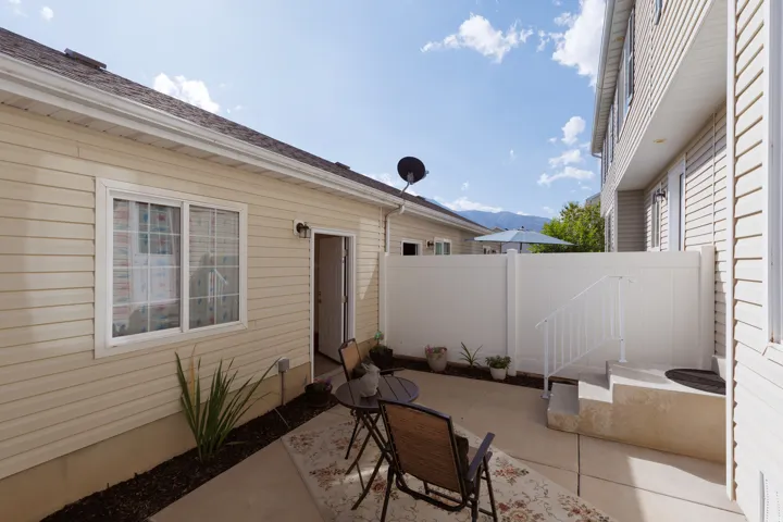Private patio space featuring a concrete surface, white vinyl fencing, and a separate entrance