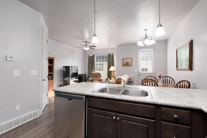 Spacious kitchen island with double basin sink, integrated dishwasher, and dark wood-finish cabinetry