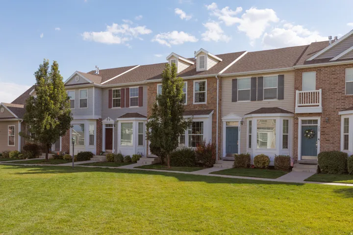 Row of townhomes featuring brick and siding exteriors, dormer windows, bay windows, and mature trees