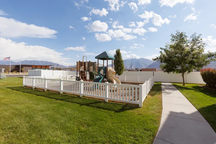Fenced play area featuring a multi-level structure with slides and climbing elements