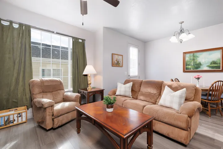 Open-concept living area with wood-finish flooring, a large window, and a ceiling fan