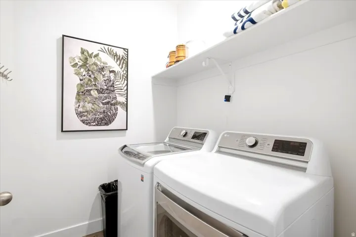 Functional laundry area featuring a white wall shelf, built-in wall hooks, and wood-finish flooring