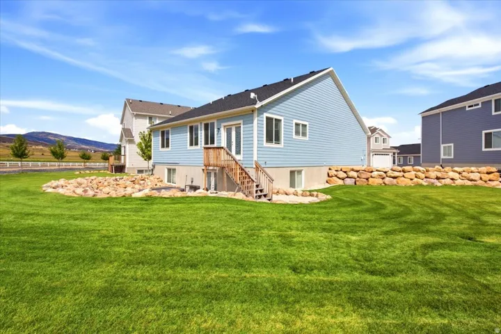 Expansive green lawn with a natural rock retaining wall