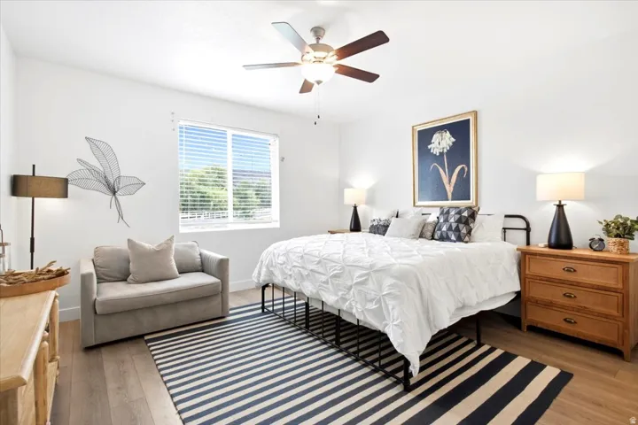 Recessed window with blinds, wood-finish flooring, ceiling fan, and painted walls