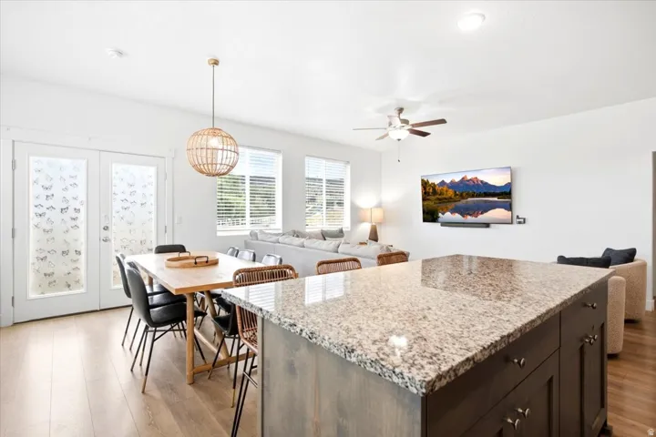 Spacious open-concept living area featuring light wood-finish flooring, a kitchen island with a stone countertop, and white walls