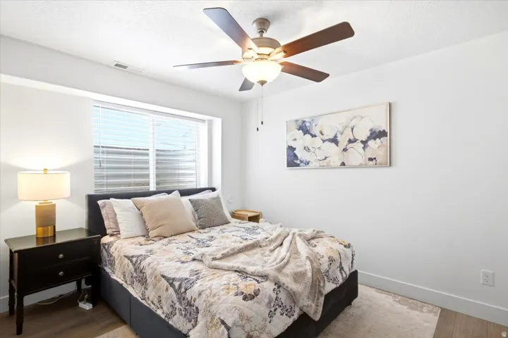 Recessed window with blinds, wood-finish flooring, and a ceiling fan with integrated lighting