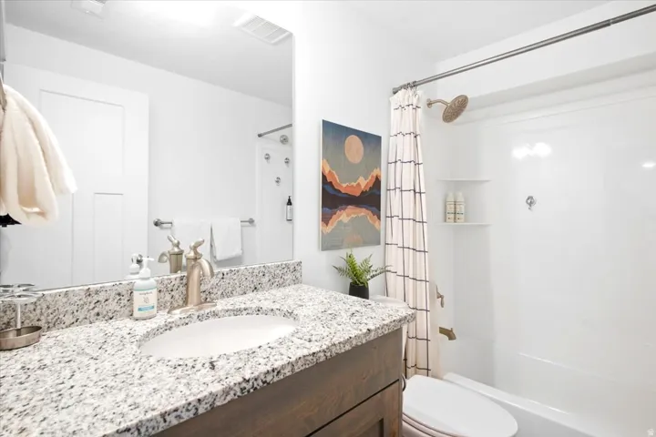 Vanity with a granite countertop, undermount sink, and brushed nickel faucet