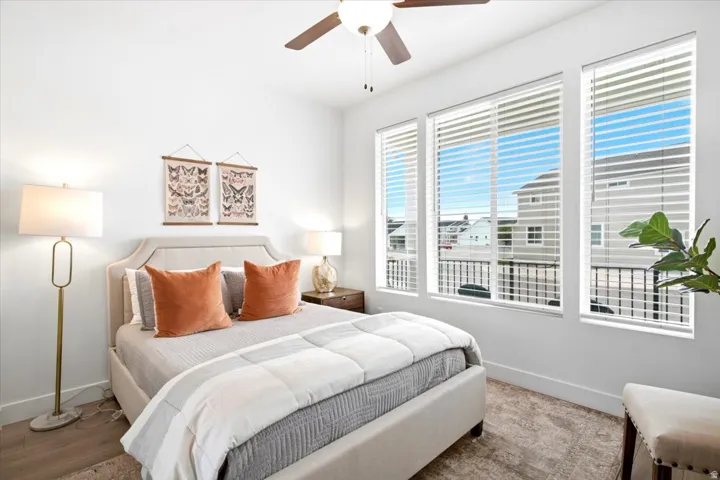 Wood-finish flooring, ceiling fan, and three large windows with white blinds