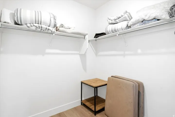 White walls, light wood-finish flooring, and built-in closet shelving