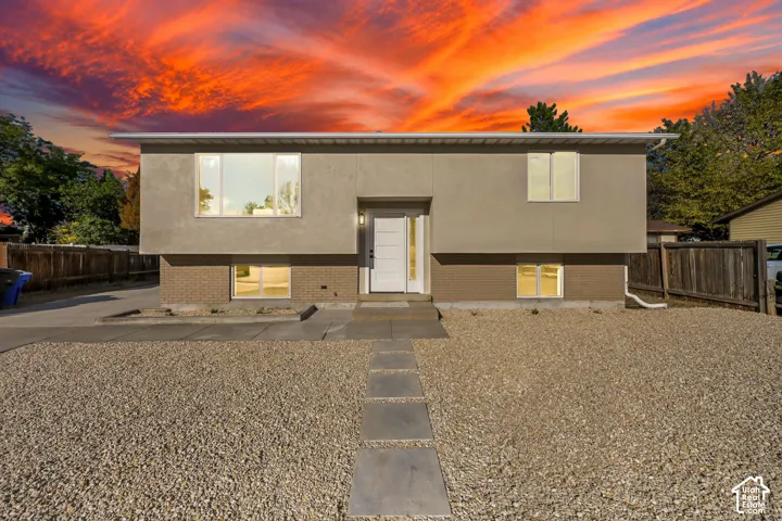 Contemporary exterior with stucco and brick accents, multiple large windows, and a white entry door