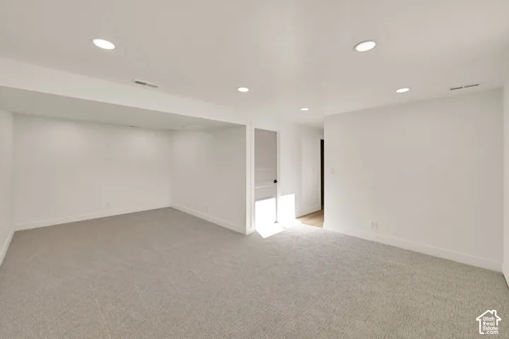 Recessed ceiling lighting, light gray carpeting, white walls, and white trim throughout