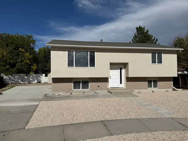 Two-story residence featuring a stucco and brick exterior, white framed windows, and a paved driveway