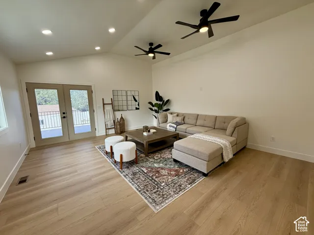 Vaulted ceilings with recessed lighting, wood-finish flooring, and French doors opening to a balcony