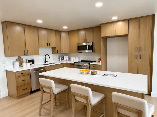 Expansive kitchen with wood-finish cabinetry, white countertops, stainless steel appliances, and a central island