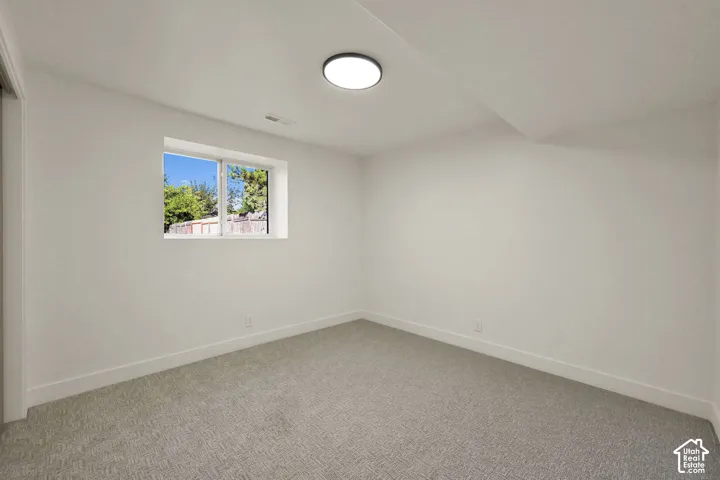 Recessed window with white trim, light-colored walls, and gray patterned carpeting