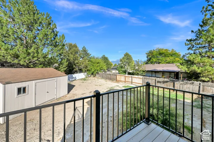 Expansive backyard featuring a storage shed with a shingled roof, a wooden privacy fence, and mature trees