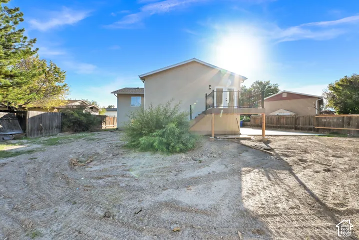 Rear exterior featuring an elevated deck with black railings, a concrete patio, and a spacious lot