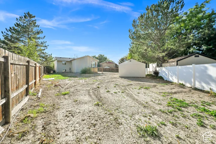 Expansive backyard area, featuring a wood fence, a vinyl fence, and a detached shed