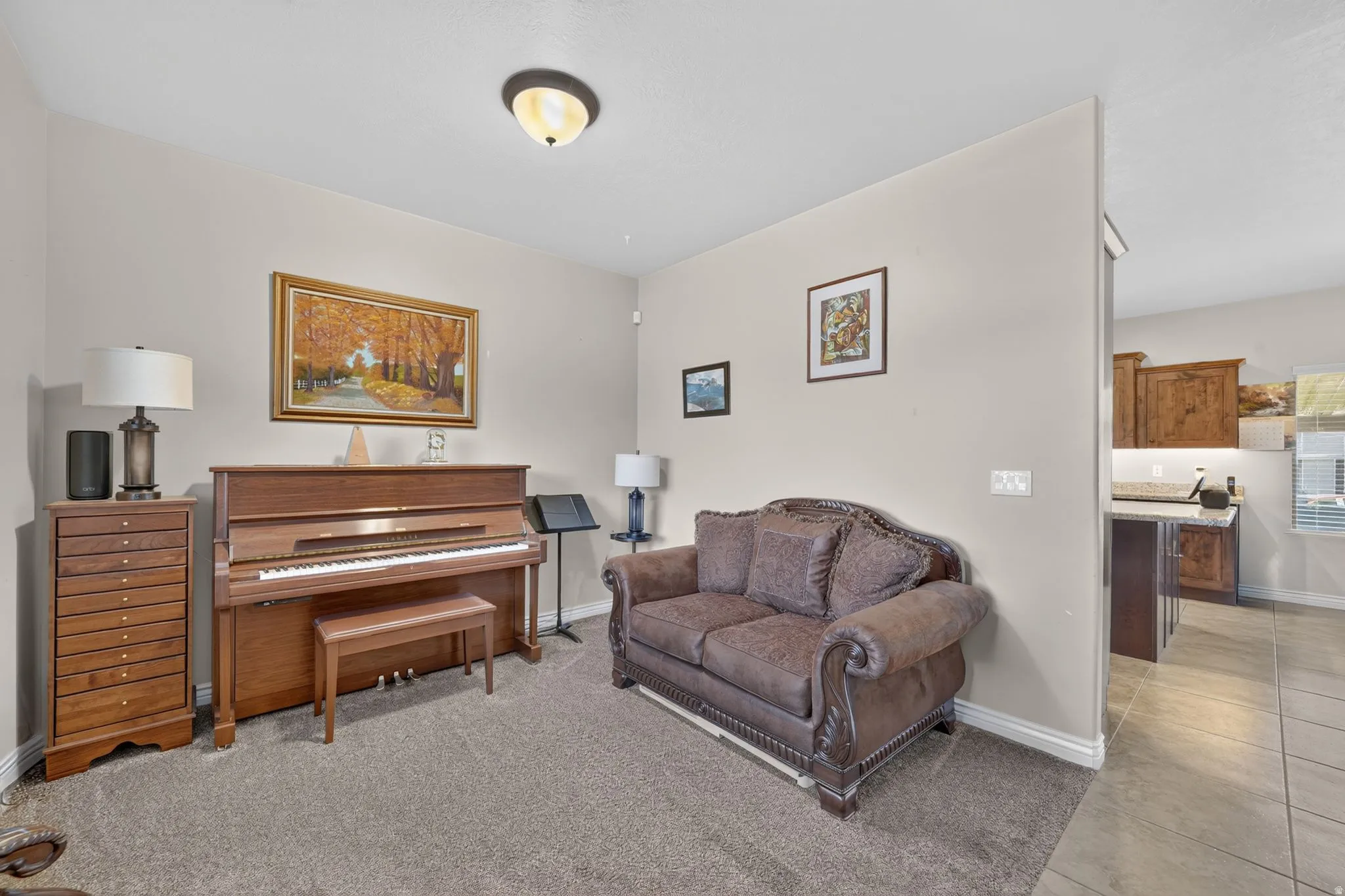 Carpeted flooring, neutral wall tones, semi-flush mount ceiling light, tiled flooring in adjacent area, wood-finish cabinetry visible in adjacent area
