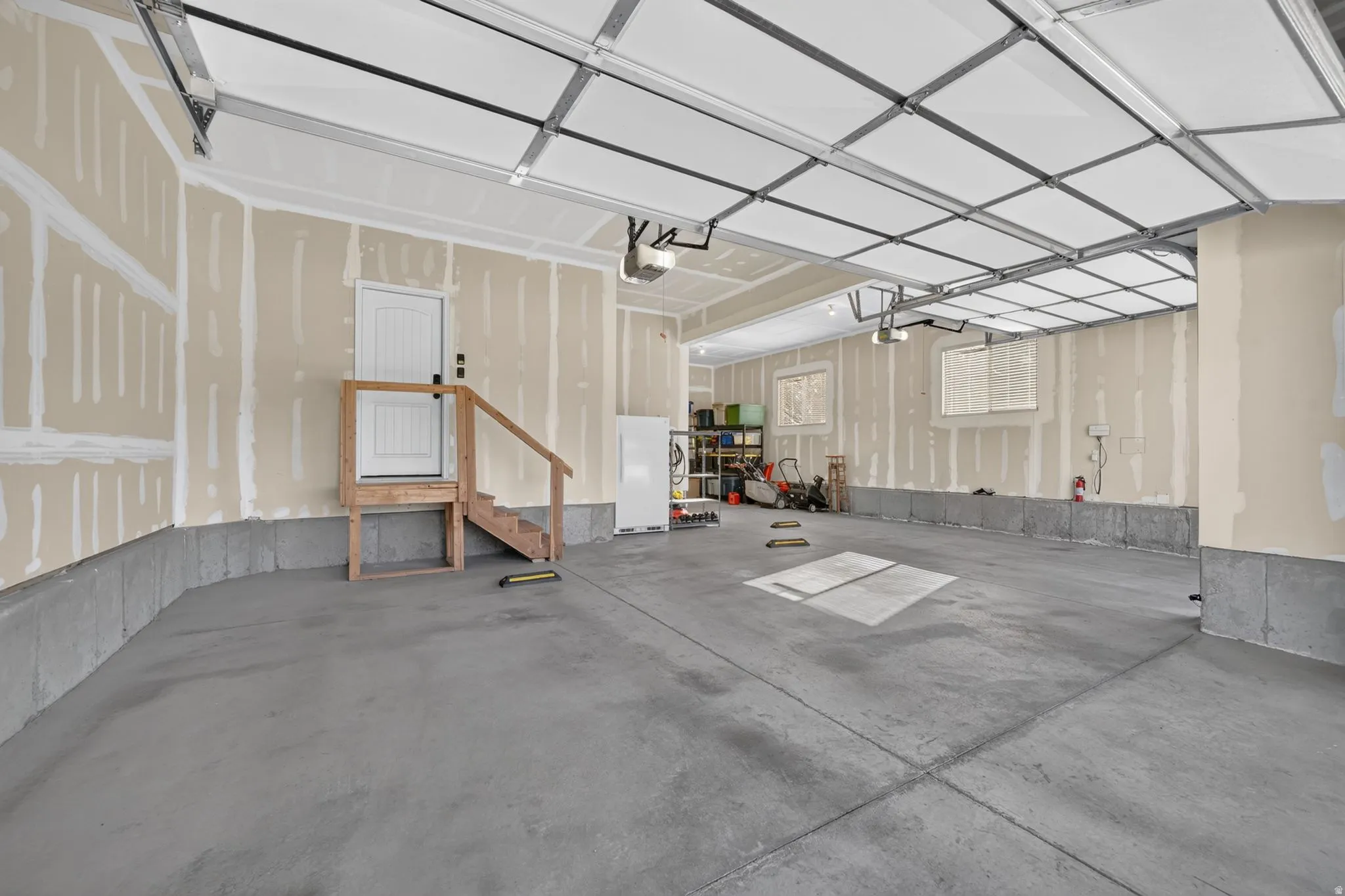 Expansive concrete flooring garage with multiple windows and a utility door