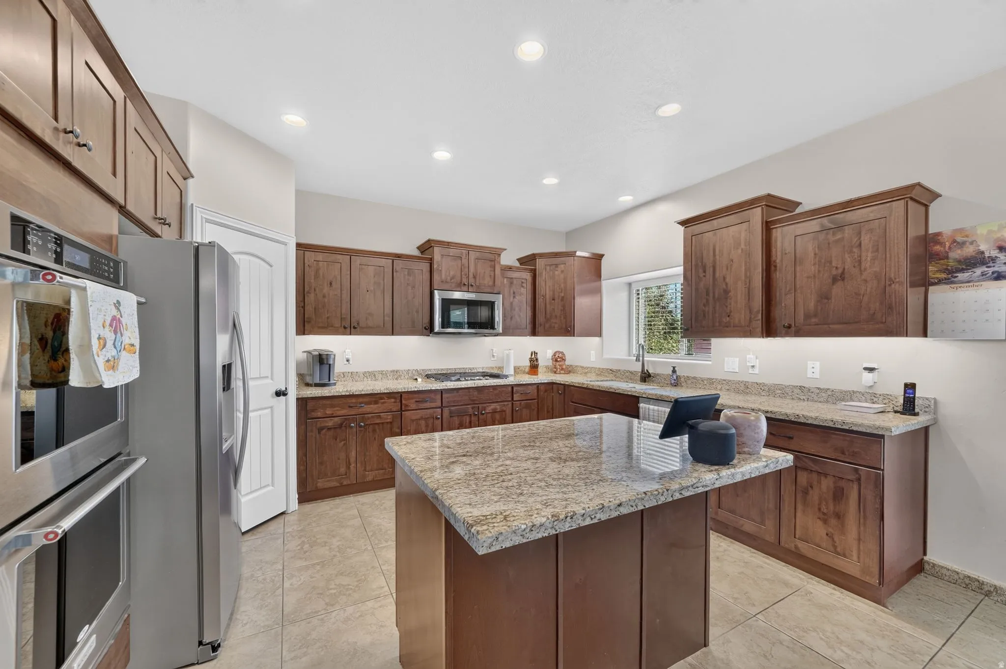 Kitchen featuring recessed lighting, extensive wood cabinetry, an island with a stone countertop, and stainless steel appliances