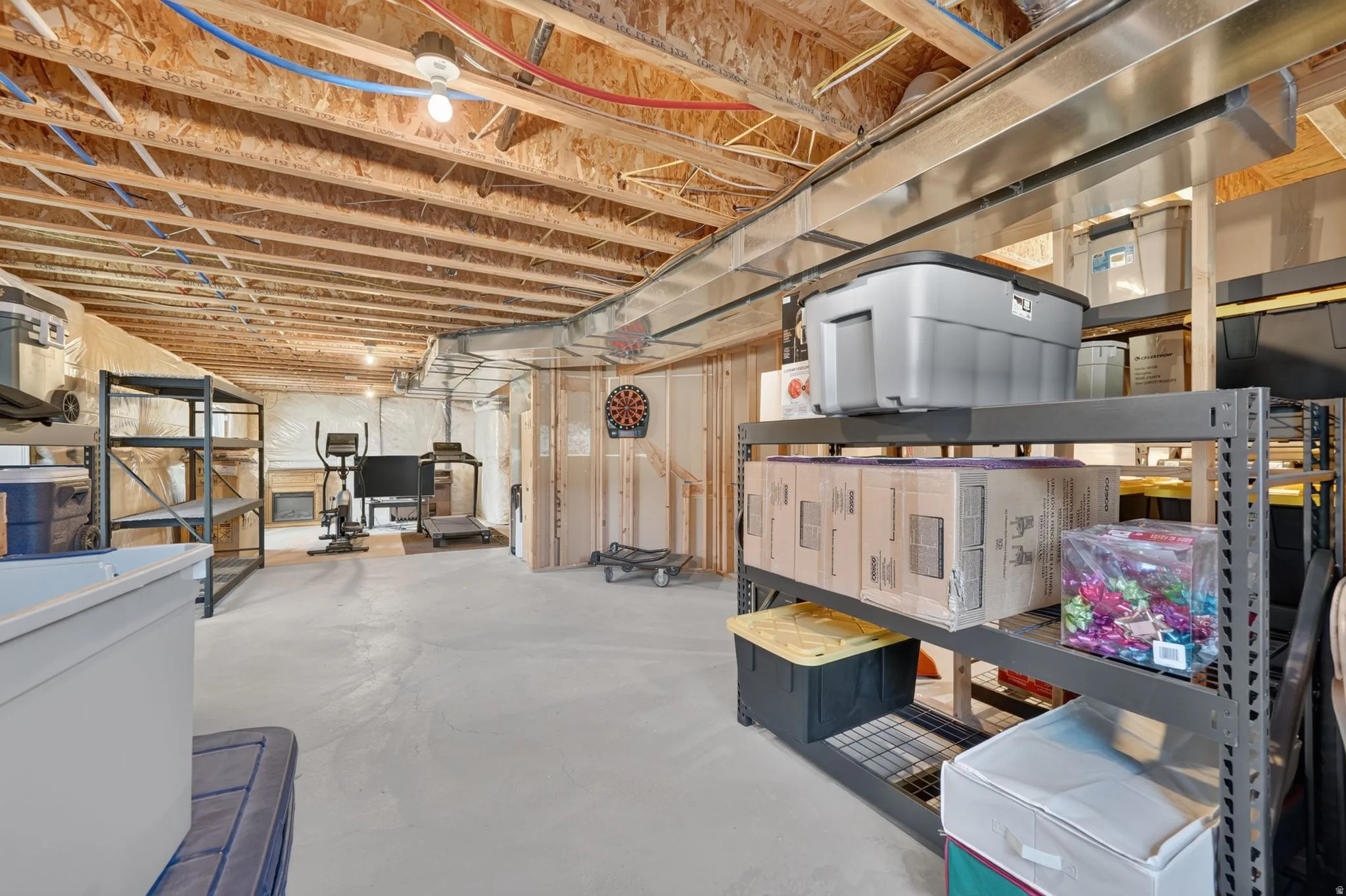 Unfinished basement featuring exposed wood joists, concrete flooring, and partial framing