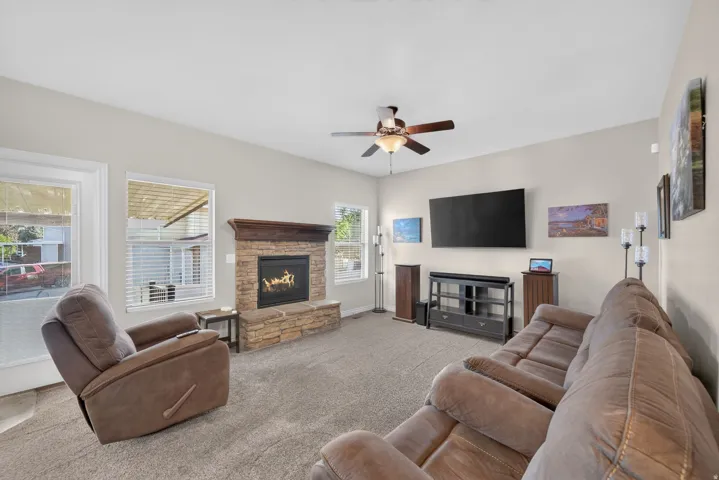 Stone-clad fireplace with a wood mantle, carpeted flooring, and multiple windows