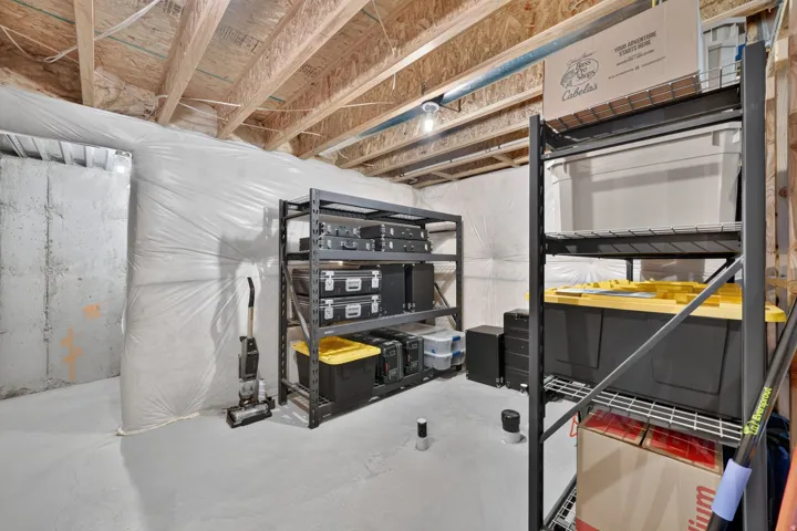 Exposed ceiling joists with insulation, concrete slab flooring, and built-in metal shelving