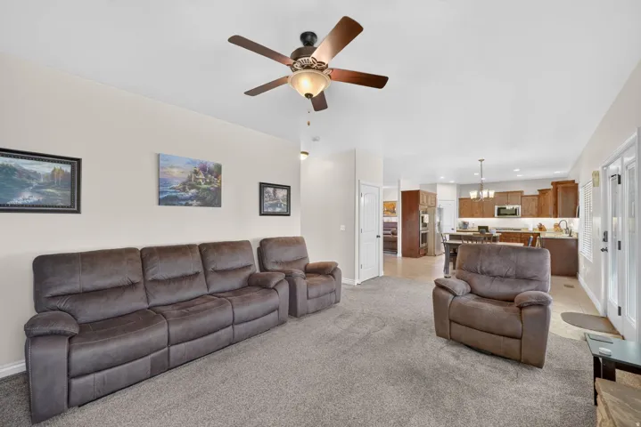 Open-concept living space featuring neutral tone walls, recessed lighting, and a ceiling fan with integrated lighting