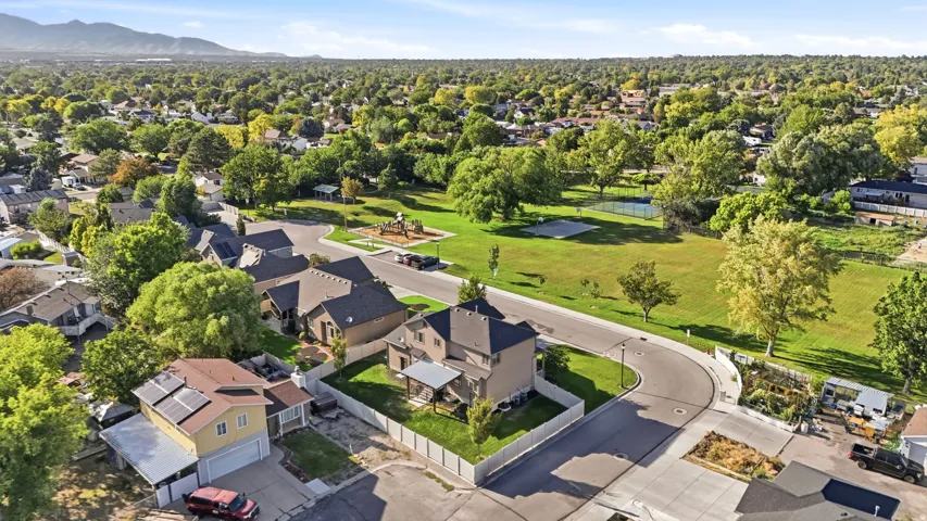Aerial perspective showcasing a residential area with mature trees and mountain backdrop