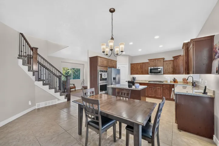 Kitchen with wood cabinetry, stainless steel appliances, a kitchen island with granite-style countertop, and tile flooring