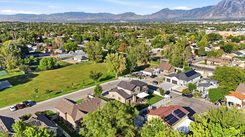 Expansive green space bordered by mature trees and residential properties, with distant mountains